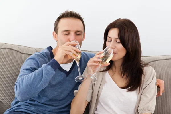 Расслабленная пара пьет шампанское на диване — стоковое фото