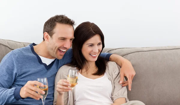 Веселая пара пьет шампанское на диване — стоковое фото