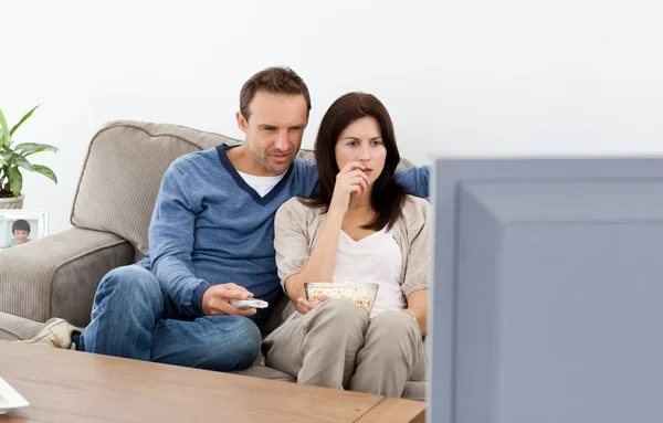 Casal atento assistindo a um filme de terror na televisão — Fotografia de Stock