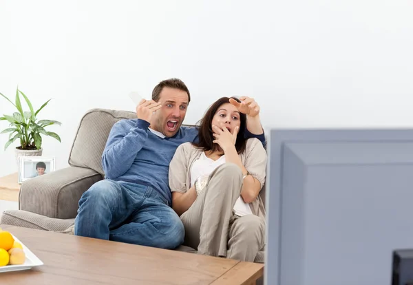 Casal assustado assistindo um filme de terror na televisão — Fotografia de Stock