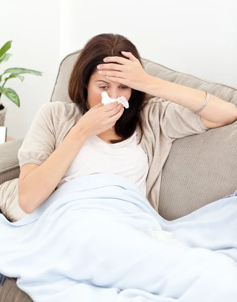 Trött kvinna känner hennes temperatur när hon blåser näsan — Stockfoto
