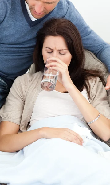Mujer enferma bebiendo agua acostada en el sofá —  Fotos de Stock