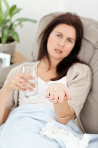 生病的女人在沙发上吃她的药 — 图库照片