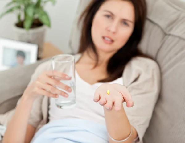 Nahaufnahme einer Frau, die ihre Medizin auf dem Sofa einnimmt — Stockfoto