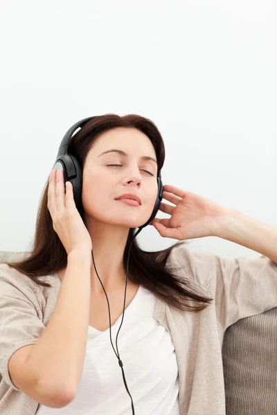 Vyrovnaná žena poslechu hudby na pohovce — Stock fotografie