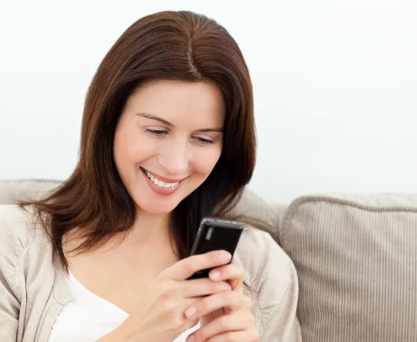 Mulher atraente lendo um sms em seu telefone celular — Fotografia de Stock
