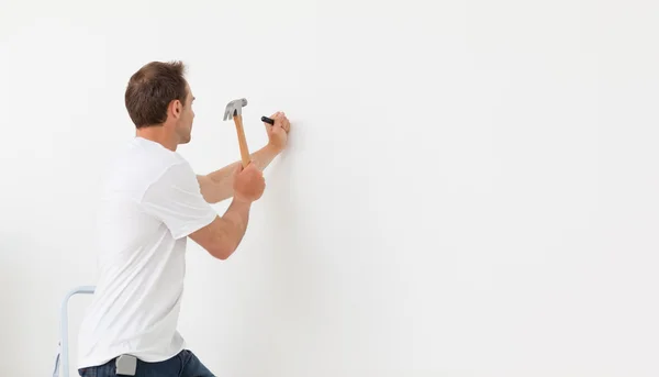 Rückansicht eines Mannes, der gegen eine weiße Wand hämmert — Stockfoto