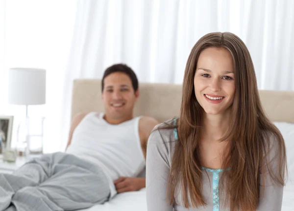 Pretty girl sitting on the edge of her bed with her boyfriend — Stock Photo, Image