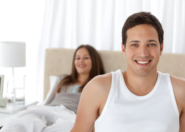 Handsome man on the edge of the bed with his girlfriend — Stock Photo, Image
