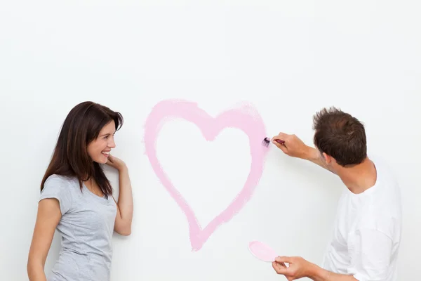 stock image Cute woman looking at her boyfriend painting a heart