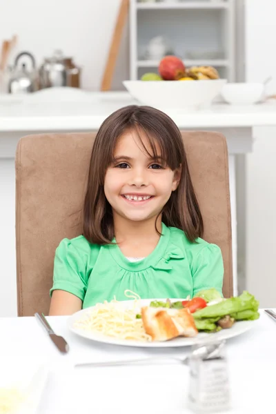 Schattig klein meisje eten pasta en salade — Stockfoto