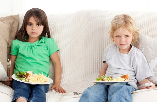 Irmão e irmã sérios jantando no sofá — Fotografia de Stock