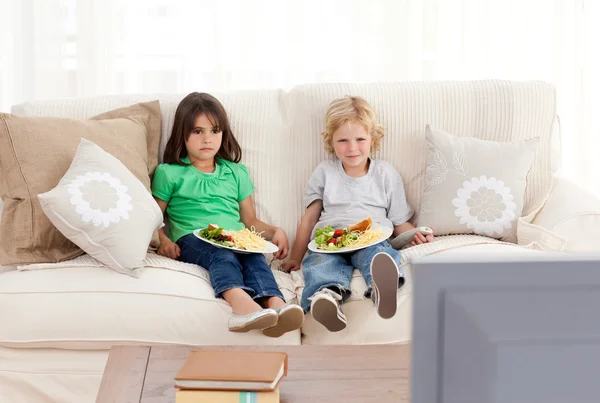 Lindo hermano y hermana cenando en el sofá —  Fotos de Stock