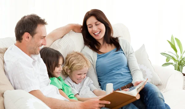 Happy parents looking at a photo album with their children — Stock Photo, Image