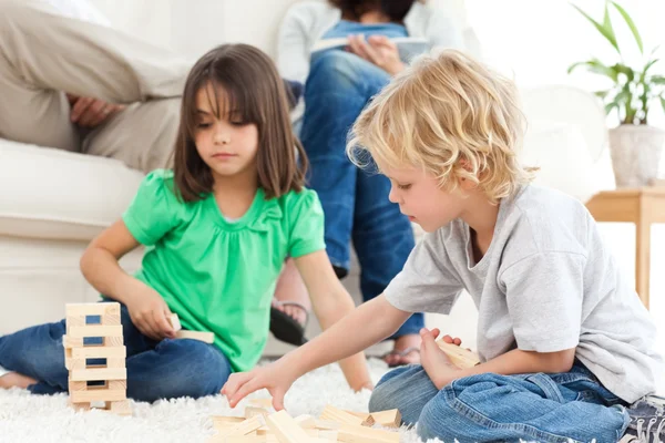 Cute brother and sister playing with dominoes on the floor — Stock Photo, Image