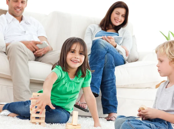 Niños felices jugando con dominó en la sala de estar —  Fotos de Stock