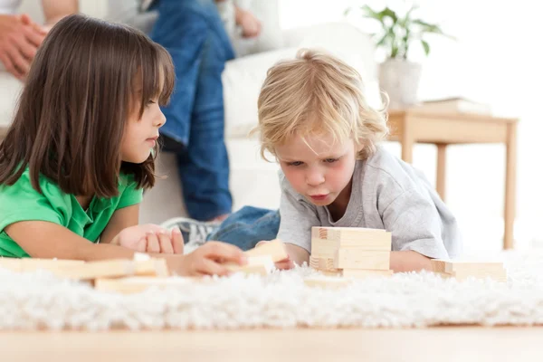 Süßer kleiner Junge spielt Dominosteine mit seiner Schwester auf dem Fußboden — Stockfoto