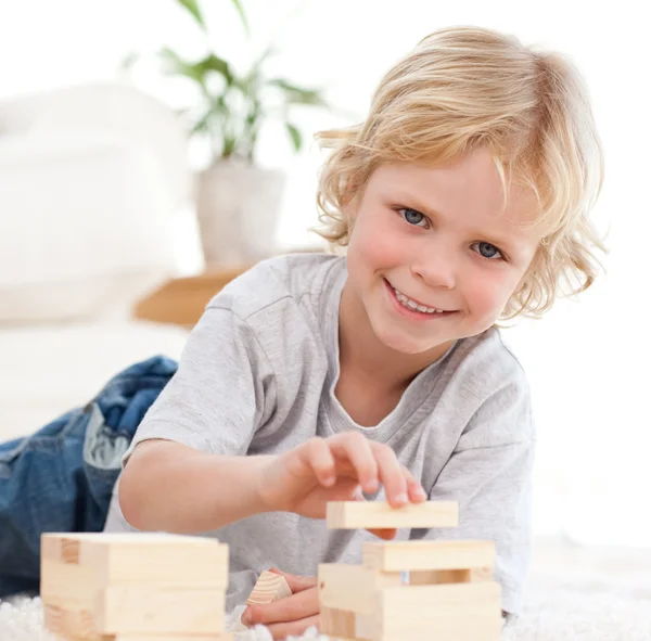 Fröhlicher Junge spielt mit Dominosteinen, die auf dem Boden liegen — Stockfoto