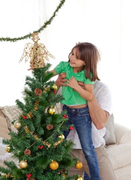 Padre atento sosteniendo a su hija para decorar la Navidad — Foto de Stock