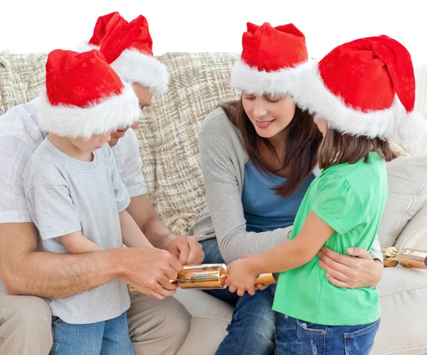 Family opening crackers together on the sofa — Stock Photo, Image