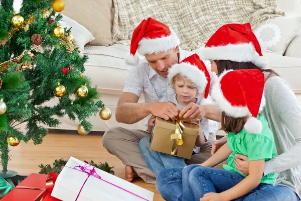 床に座ってのクリスマスのギフトを開く家族 — ストック写真