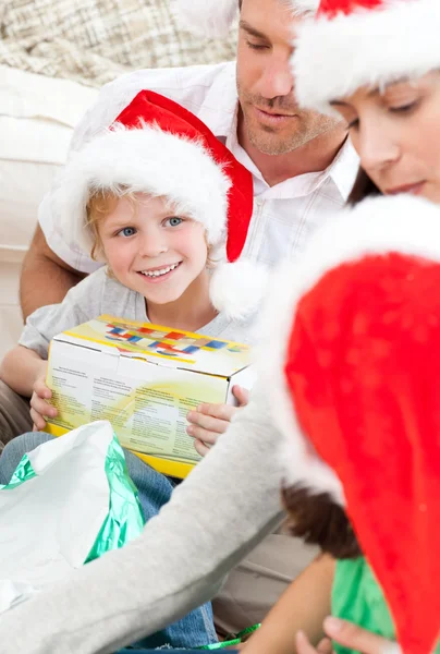 Elinde Noel hediyesi tutan mutlu çocuk yerde oturuyor. — Stok fotoğraf