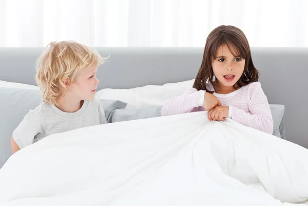 Очаровательные дети играют вместе на кровати своих родителей — стоковое фото