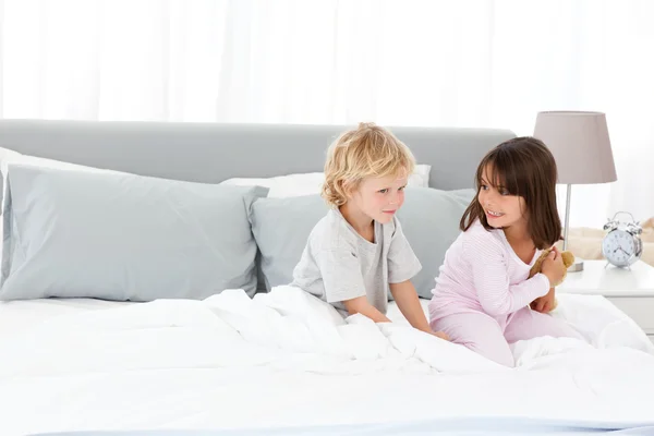 Мальчик играет со своей сестрой на кровати родителей — стоковое фото