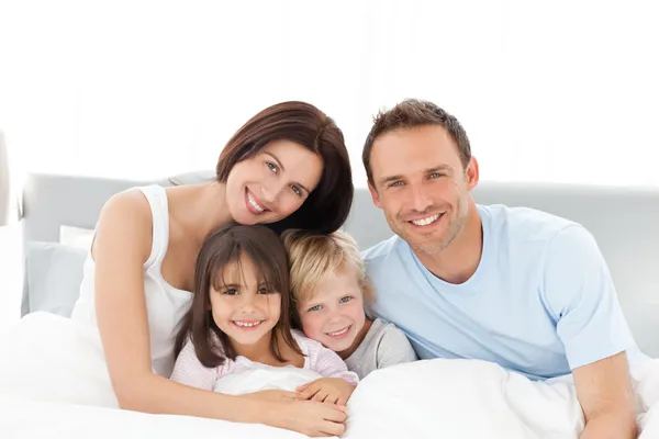Retrato de uma família feliz sentada na cama — Fotografia de Stock