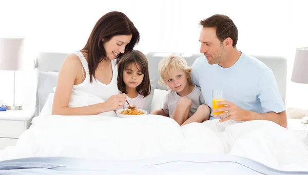 Веселая семья, завтракающая на кровати — стоковое фото