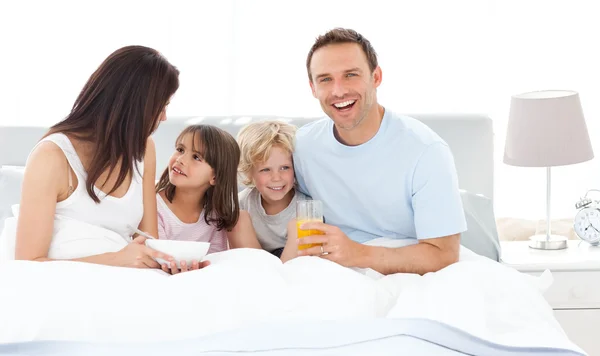Happy dad having breakfast with his family on his bed — Stock Photo, Image