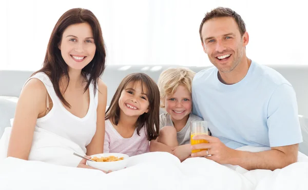 Веселая семья завтракает вместе на кровати — стоковое фото