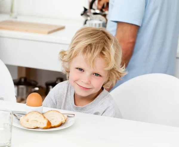 Niño comiendo huevo hervido y pan en el desayuno —  Fotos de Stock