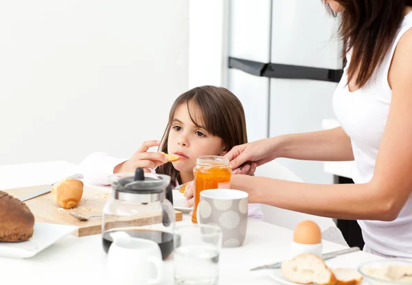 Bella madre che dà pane tostato con marmellata a sua figlia per il brea — Foto Stock