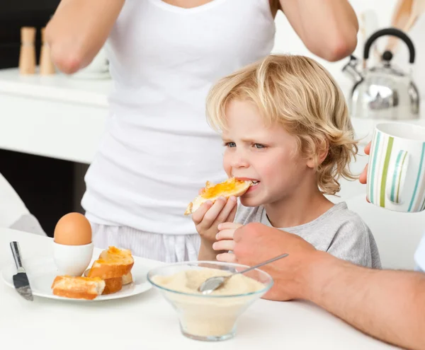Allvarliga pojken äta en toast med marmelad under frukost — Stockfoto