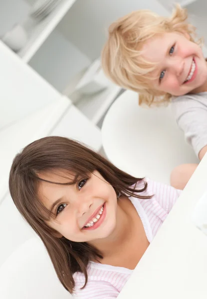 Cute brother and sister sitting at a table in the kitchen — Stock Photo, Image