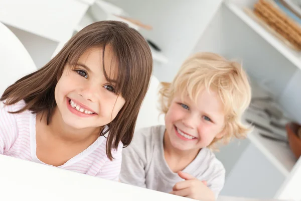 Happy children sitting at a table in the kitchen — Stock Photo, Image
