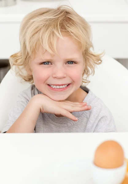 Schattige kleine jongen zitten aan een tafel te eten een gekookt ei — Stockfoto