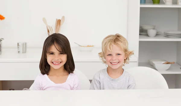 Schöne Bruder und Schwester sitzen an einem Tisch in der Küche — Stockfoto