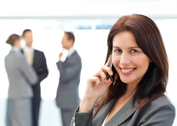Симпатична бізнес-леді по телефону, поки її команда обговорює — стокове фото