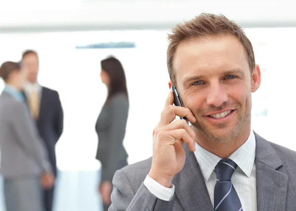 Gelukkig zakenman aan de telefoon terwijl het zijn team werken — Stockfoto