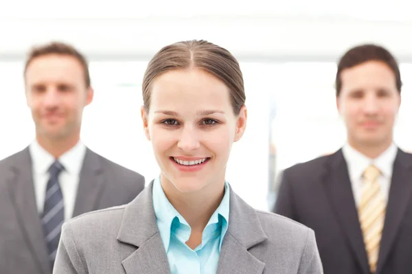 Cheerful businesswoman standing in front of two businessmen — Stock Photo, Image