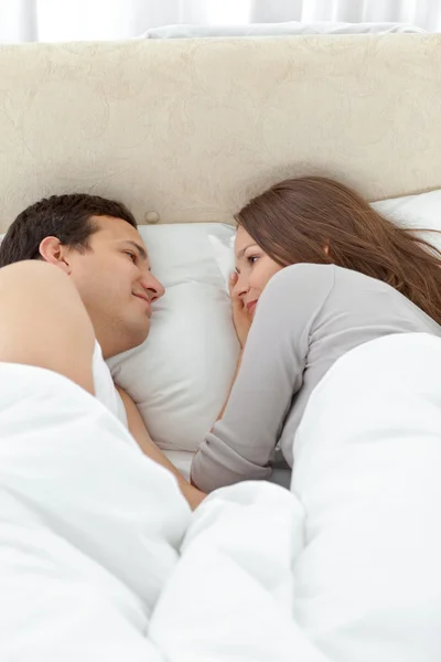 Милая пара смотрит друг на друга, расслабляясь на кровати — стоковое фото