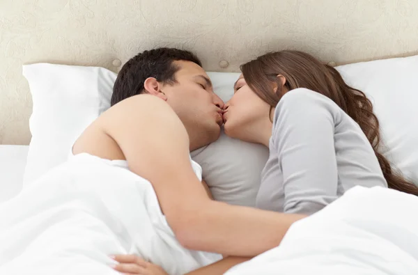 Krásný pár, líbání v náručí na postel — Stock fotografie