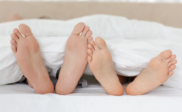 Primer plano de los pies de la pareja mientras se relaja en su cama — Foto de Stock