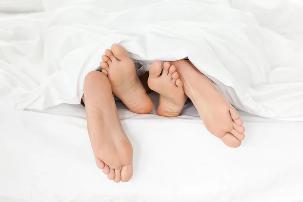 Primo piano dei piedi di coppia mentre si divertono nel loro letto — Foto Stock
