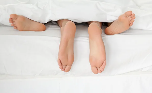 近拍的夫妇的脚抱在自己的床上时 — 图库照片