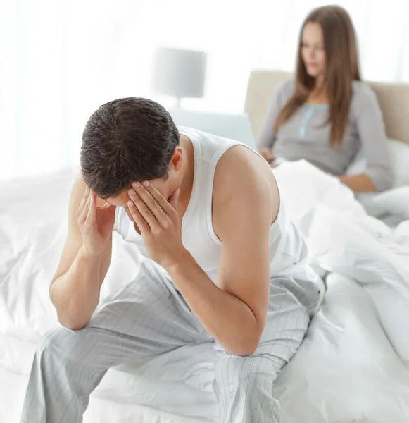 Estressado homem sentado em sua cama, enquanto sua namorada trabalhando em — Fotografia de Stock