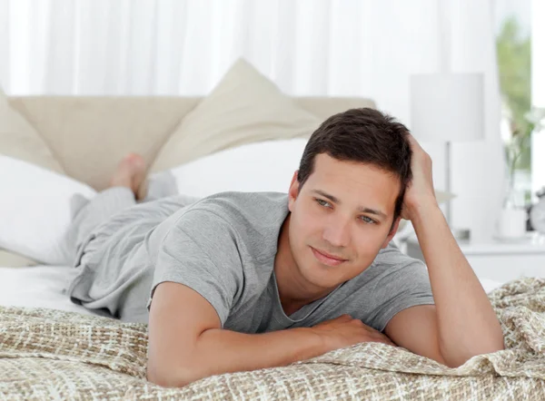 Nachdenklicher junger Mann liegt auf seinem Bett — Stockfoto