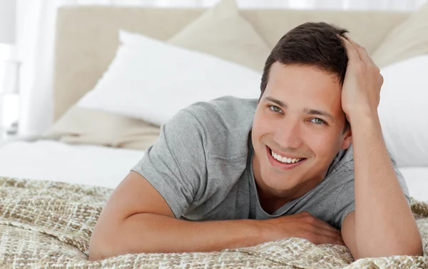 Радостный человек лежит на краю кровати у себя дома — стоковое фото